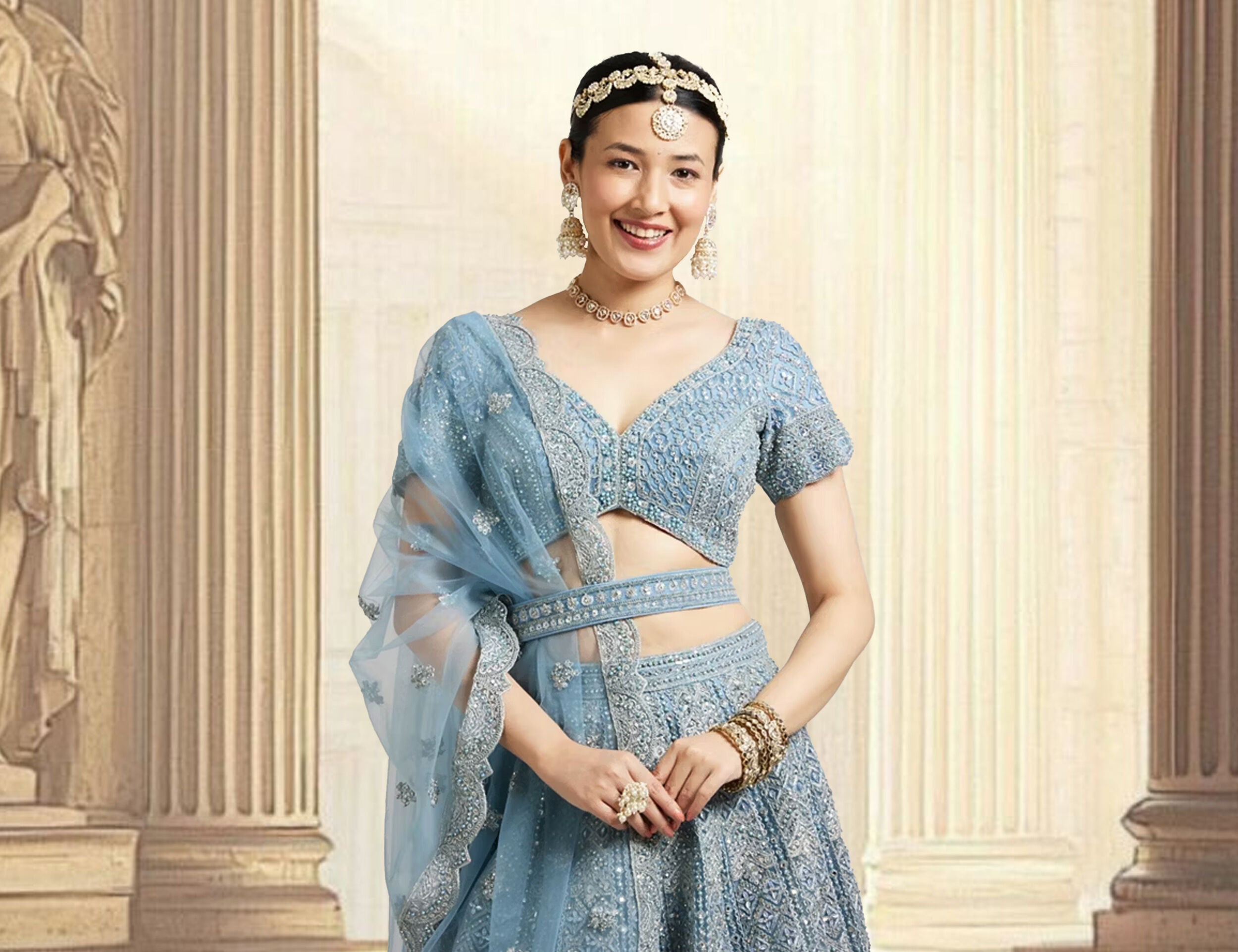 A stylish woman modeling a powder blue lehenga, accessorized with gold bangles and a silver necklace